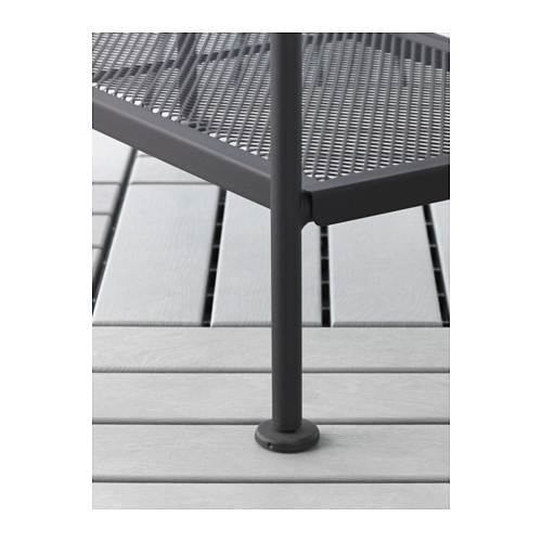 Primer plano de la pata de una silla de exterior moderna, con un acabado negro mate y un protector de suelo circular.