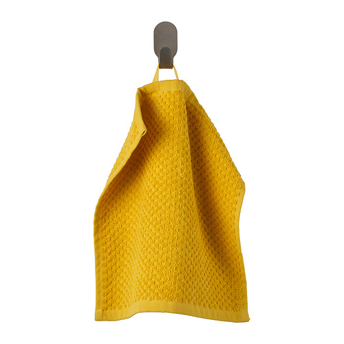 Toalla GULVIAL de color amarillo brillante colgada en un gancho de madera, hecha de suave algodón 100%, con un patrón texturizado y un diseño doblado.