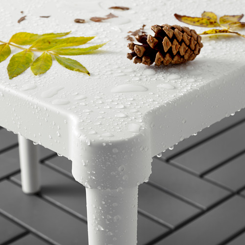 Mesa infantil de plástico blanco al aire libre, con gotas de agua, piña y hojas encima. Perfecto para artes, manualidades y bocadillos.