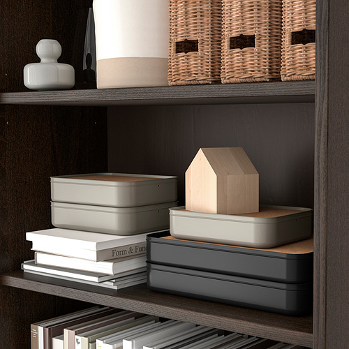 Estantería organizada con cajas grises, cestas de mimbre, libros y decoración de madera.