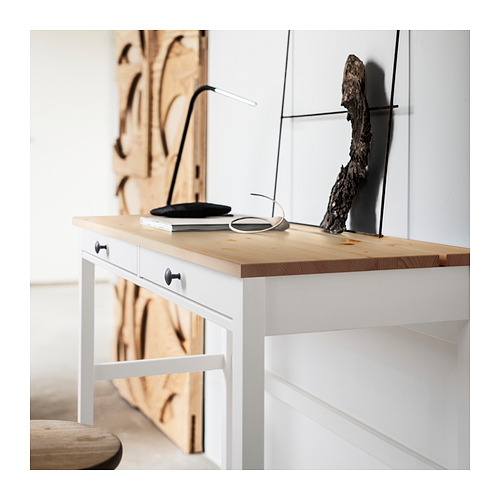 Moderno escritorio de madera blanca con tapa de madera clara, lámpara minimalista, libro y decoración circular.