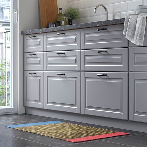 Cocina moderna con gabinetes grises, encimera de mármol y una colorida alfombra a rayas en el frente, que brindan un toque vibrante al elegante diseño.