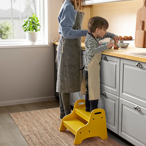 Un niño en un taburete alcanza los cupcakes en la cocina.