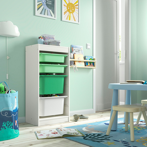 Un mueble de almacenaje TROFAST en color blanco con cubos verdes, tiene estantes abiertos y se coloca en una habitación muy iluminada, junto a un pequeño juego de mesas y sillas.