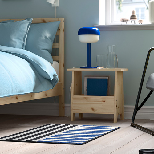Alfombra de rayas azules y negras VÄNDPLATS junto a la cama de madera, más pequeña que la cama, pelo suave y bajo, respaldo de goma para agarre.