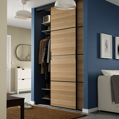 Dormitorio moderno con armario SKYTTA, puertas correderas, zapatero blanco, mesa negra, espejo grande, paredes gris azulado.