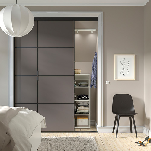 Dormitorio moderno con puertas corredizas de armario SKYTTA, silla negra, decoración minimalista.