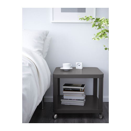 Mesita de noche moderna con ruedas, libros, una taza y un reloj. Fácil de mover y organizado con un estante separado.