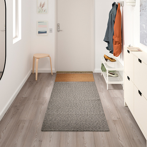 Entrada moderna con alfombra de algodón gris TIPHEDE, entre taburete y zapatero.