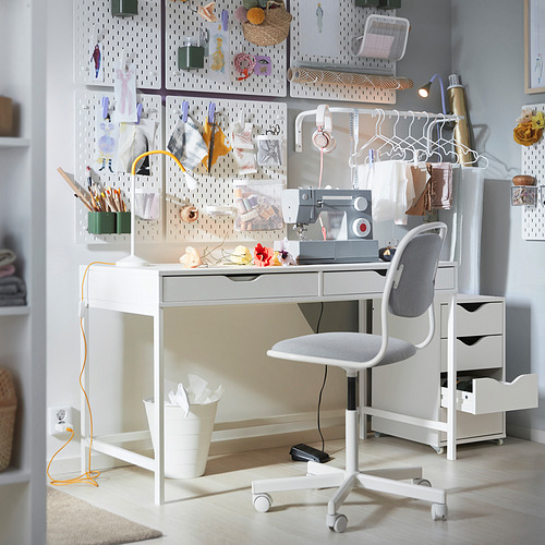 Moderno escritorio blanco con patas grises, cuatro cajones y silla. Tablero perforado con herramientas. Configuración minimalista.
