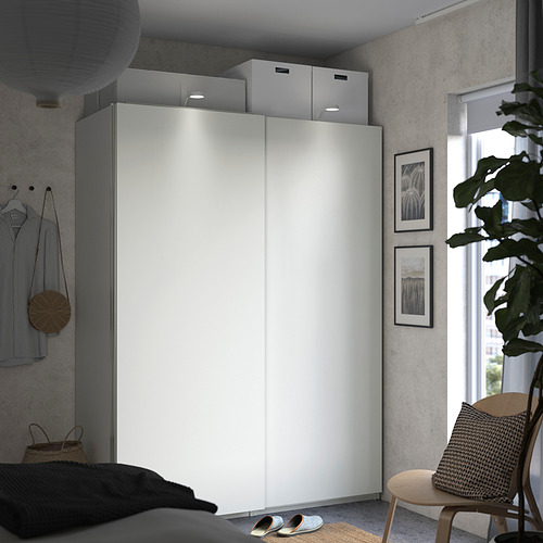 Dormitorio moderno y minimalista, un elegante armario blanco PAX con puertas correderas y almacenamiento abierto.