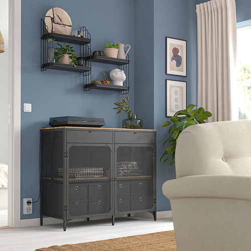 Estantería de metal negro con plantas, decoración y electrónica, encaje en la esquina de la habitación junto a un sillón beige.