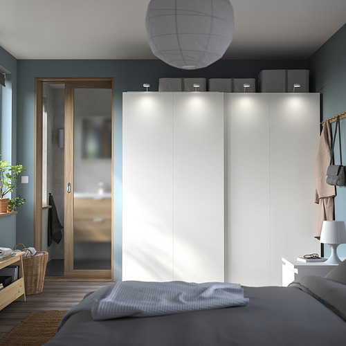Dormitorio moderno con un armario PAX blanco, ropa de cama gris y puerta decorativa de madera.