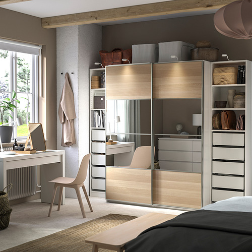 Dormitorio moderno con un armario PAX beige, con puertas correderas con espejos, varios estantes y cajones. Incluye escritorio, silla y accesorios.