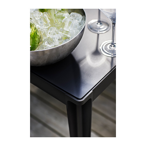 Mesa de exterior negra con cuenco metálico con hielo y vasos. Diseño moderno con bordes elegantes.