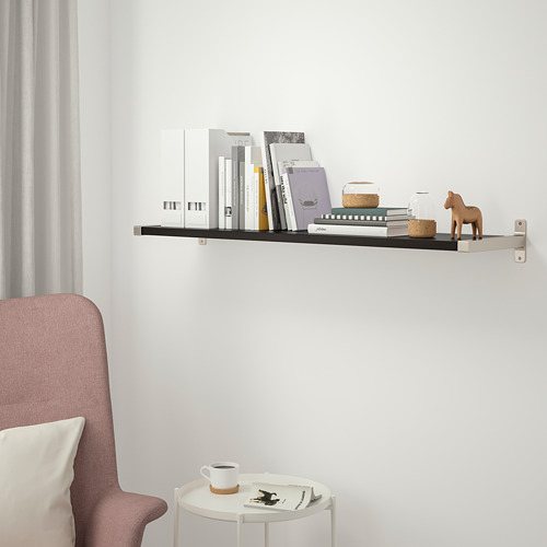Habitación minimalista con estantería BERGSHULT, libros, silla rosa, taza de café.