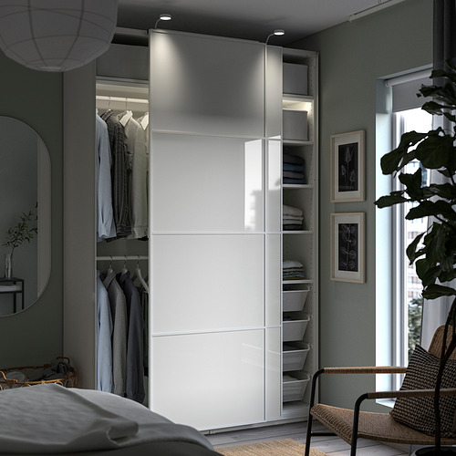 Modern bedroom with white PAX wardrobe, sliding doors, built-in lighting, and organized clothes.