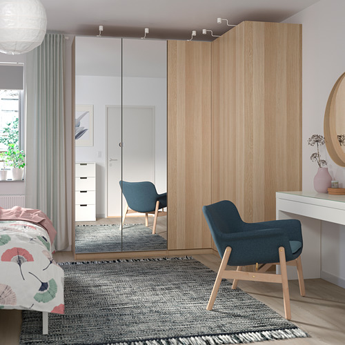 Dormitorio moderno con muebles de madera clara, gran armario FORSAND, sillas azules y alfombra funky.