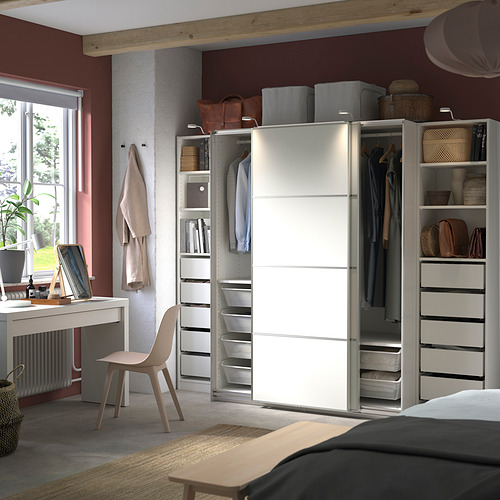 Dormitorio moderno con armario PAX blanco, puertas correderas, ropa y estantes de almacenamiento.