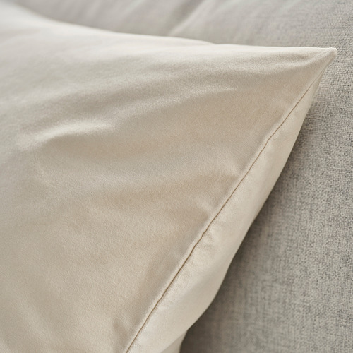 Primer plano de una lujosa funda de cojín de terciopelo beige liso sobre una cama, con una textura suave y un acabado elegante.
