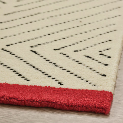 Esquina de alfombra de precipicio, líneas negras sobre crema, borde rojo, textura de lana suave