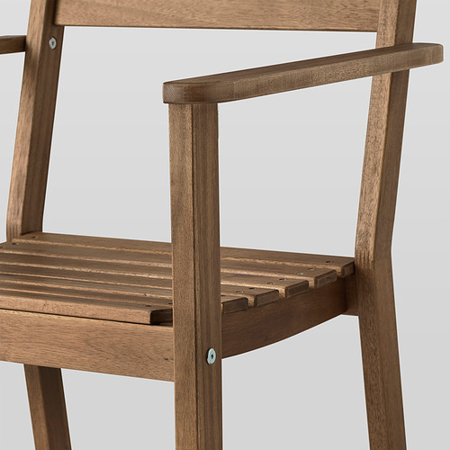 Primer plano de una robusta silla de madera de acacia, mostrando los detalles del reposabrazos y del asiento, destacando la artesanía y la calidad.