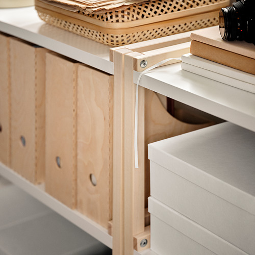 Una estantería de madera clara EKENABBEN con estantes blancos que contienen cajas y una cámara en la parte superior.