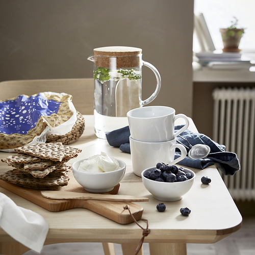 Preparación del desayuno con waffles, arándanos, yogur y tazas y jarra de IKEA 365+ sobre una mesa de madera.