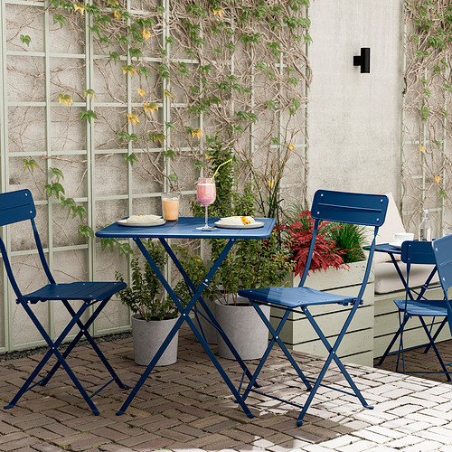 Patio azul sobre ladrillos. Acero plegable y duradero. Con platos y bebidas.