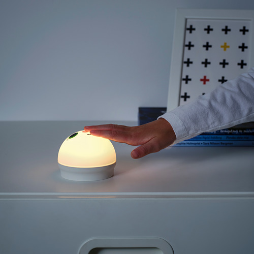 Una mano enciende la luz nocturna táctil KORNSNÖ en un cajón, revelando su suave brillo.