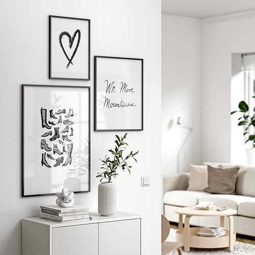 Sala de estar moderna con muebles blancos, tres obras de arte enmarcadas: corazón, botas, montañas y decoración vegetal.