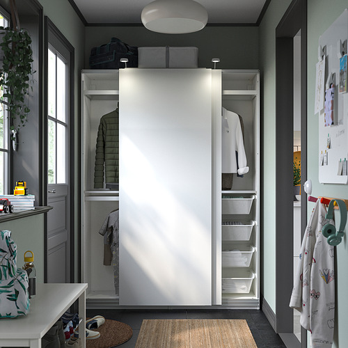 Armario moderno con puertas corredizas, estantes de almacenamiento y contenedores blancos. Plantar y colgar abrigos cerca.