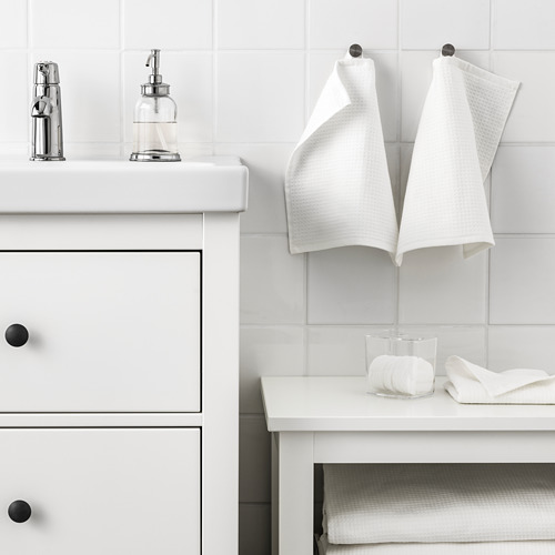 Baño moderno con decoración blanca, toallas y dispensador de jabón de vidrio.