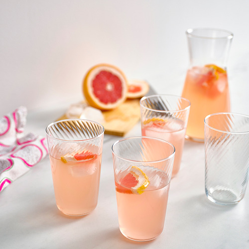 Cuatro vasos de vidrio con bebidas de pomelo rosa, hielo y diferentes alturas en una mesa.