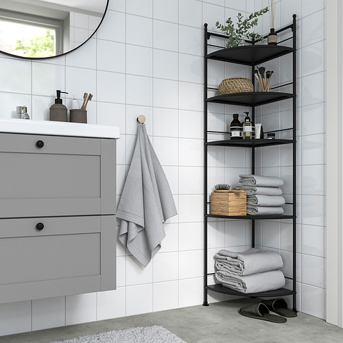 Estante esquinero FRÖSJÖN negro en el baño, que contiene toallas, artículos de tocador y decoración.
