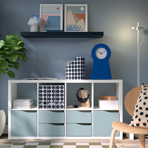 Sala de estar moderna con estante de pared LACK bLACK, reloj azul, decoración de lunares, planta en maceta, silla de madera clara y unidad de almacenamiento blanca.
