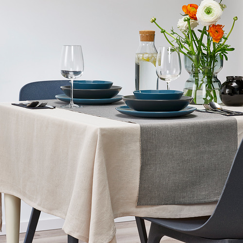 Mesa con cuencos y copas de vino azules, con un camino de mesa gris, creando una escena gastronómica elegante.
