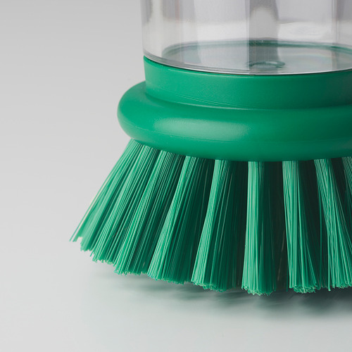 Primer plano de pincel para platos verdes con recipiente transparente.