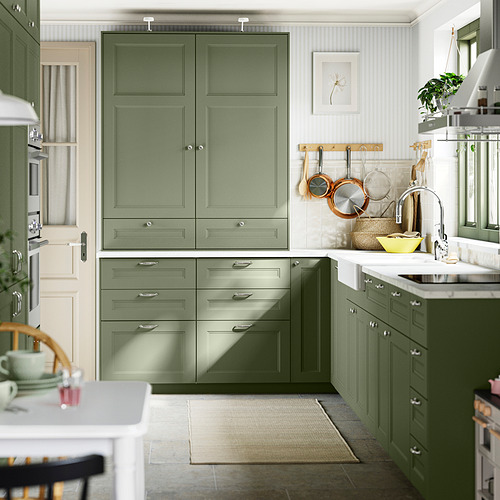 Cocina moderna con gabinetes verdes, encimeras blancas, accesorios cromados y tazón amarillo.