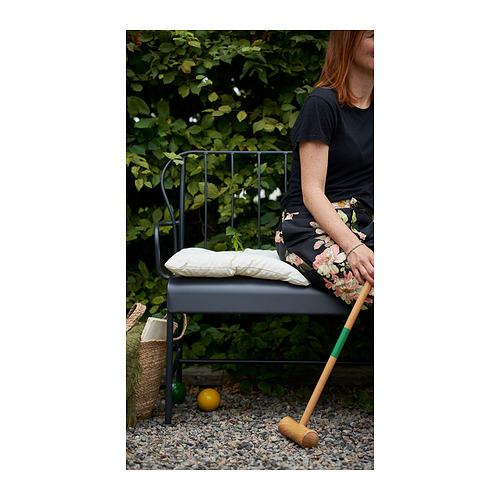 Persona sentada en una silla de jardín LÄCKÖ gris con mazo de madera, junto a una cesta sobre grava.
