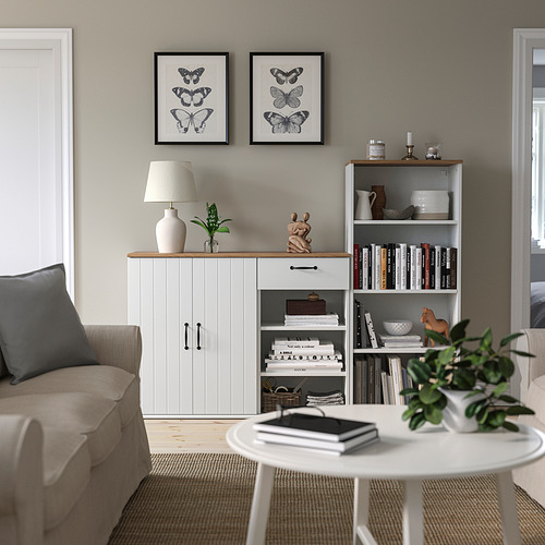Sala de estar con aparador y estantería SKRUVBY, decorada con plantas, libros y arte de mariposas, y un acogedor sofá.