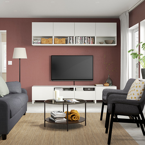 Acogedora sala de estar con paredes rojas, sofá gris, televisor de pantalla plana, mesa de centro de vidrio y sillón con cojines de lunares amarillos.