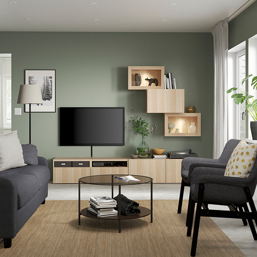 Sala de estar moderna con estantes de roble claro LAPPVIKEN, TV, sofá gris y mesa de centro redonda. Pared verde, cortinas blancas y gran ventanal.
