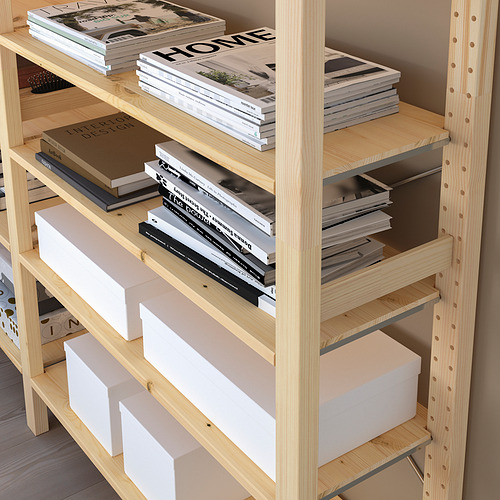 Estantería de pino con estantes ajustables que sujetan libros y cajas, apilados vertical y horizontalmente.