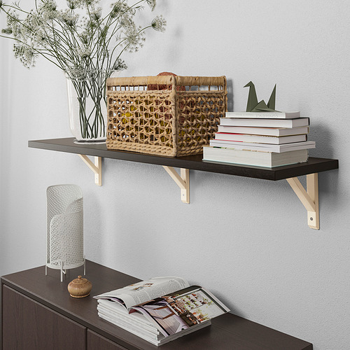 El estante montado en la pared contiene libros y decoración. Elegante y funcional, muestra los artículos de manera ordenada y eficiente.
