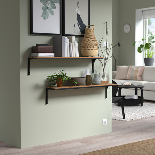 Salón moderno con estanterías de pared rústicas FJÄLLBO. El diseño de metal y madera sostiene libros, jarrones, plantas. Pared verde claro, suelo de color claro.