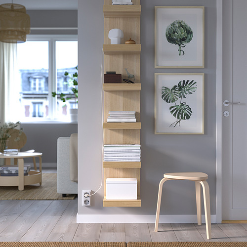 Pared azul con estante LACK, revistas, caja, lámpara, estampados de plantas, taburete. Habitación minimalista y bien iluminada.