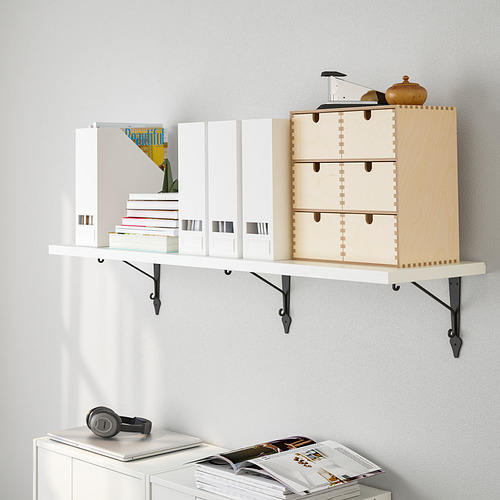 Estantería de pared con libros, una caja de madera y artículos decorativos. Organiza eficientemente y los elementos en una pared blanca.