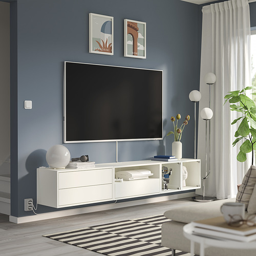 Sala de estar moderna: TV plana sobre soporte blanco, pared azul, decoración blanca, alfombra grande.