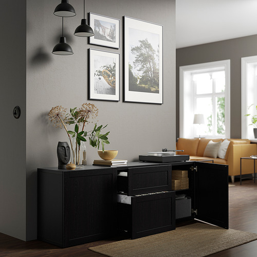 Sala de estar moderna con aparador BESTÅ negro, estantes ajustables y cajones de cierre suave. Coronado con un jarrón de flores y elementos decorativos.